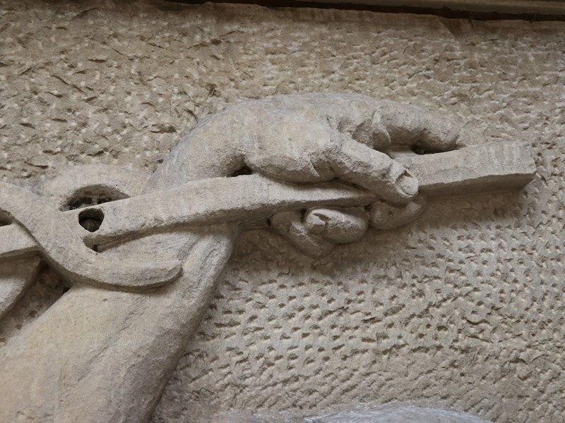 Detail of the stonework on Parliament House's facade, showing a hand reaching to the right.