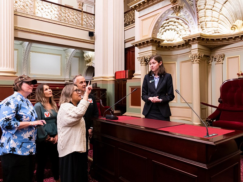 A visitor points up at a feature of the Legislative Assembly chamber.
