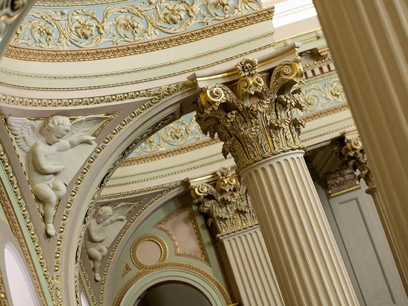 A detail of the internal columns of Parliament House with sculptures of cherubs and agapanthus