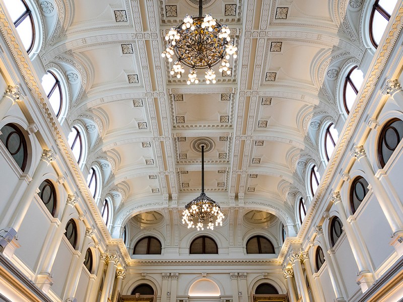 A large room with high ornate ceilings, arches and two chandeliers.