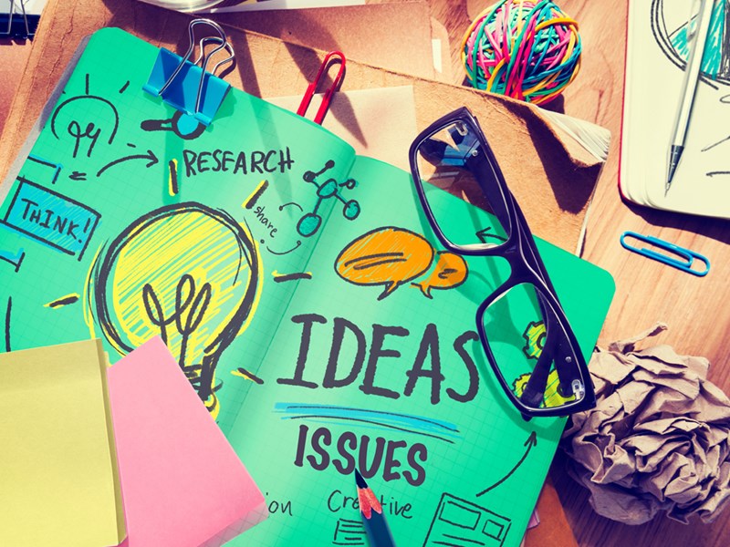 Assorted stationery and handwritten notes on coloured paper showing a brainstorming process.