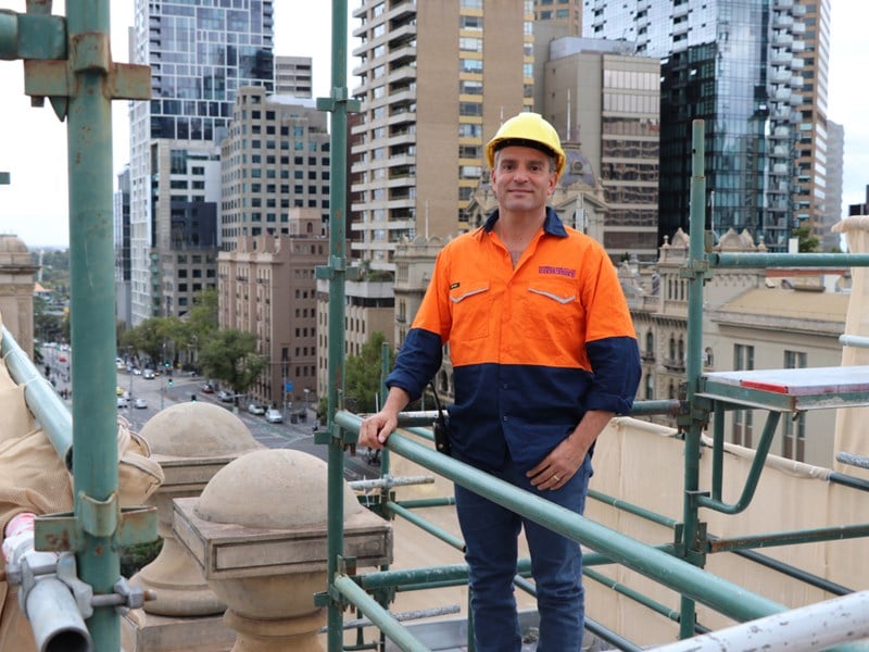 Joe Michienzi, stonemason, poses on scaffolding at the restoration worksite, overlooking the city.